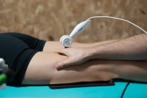fisio pasando maquina por la pierna de un paciente