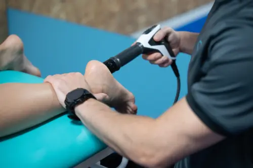 fisioterapeuta pasando maquina por el pie de un paciente