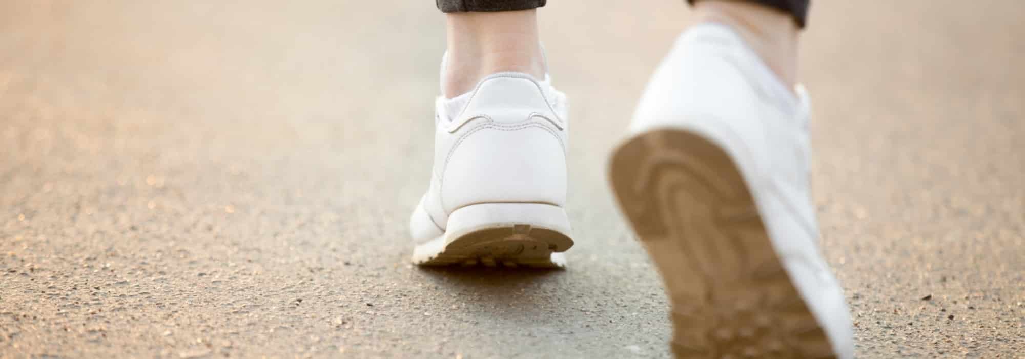 persona andando con zapatillas blancas